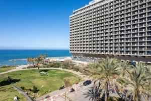 un gran edificio con palmeras frente al océano en The Vista At Hilton Tel Aviv, en Tel Aviv