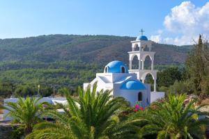 uma igreja azul e branca com uma montanha ao fundo em Lindos Village Resort & Spa - Adults Only em Líndos