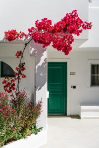 uma porta verde e flores vermelhas em frente a um edifício em Lindos Village Resort & Spa - Adults Only em Líndos