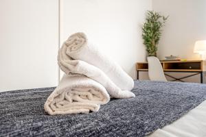 a pile of white towels sitting on a bed at Santos Mattos Guesthouse & Apartments by Lisbon with Sintra in Amadora