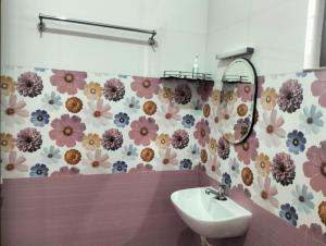 een badkamer met een wastafel en bloemen aan de muur bij Devi Kripa Residency in Varkala