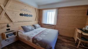 1 dormitorio con 1 cama en una habitación de madera en Hotel Villa Gaia, en Cortina dʼAmpezzo