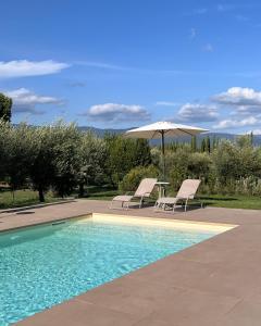 uma piscina com duas cadeiras, uma mesa e um guarda-sol em All'Ombra Del Tiglio em Pistoia