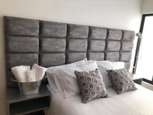 a bed with a large gray padded headboard with pillows at Beauté in Pereira