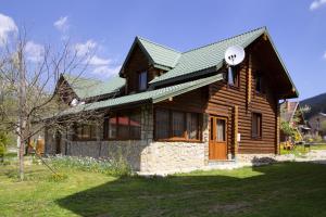 une maison en bois avec un toit vert dans l'établissement Садиба У Василини та Романа, à Bukovel