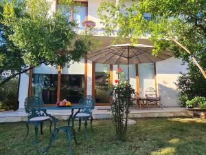 uma mesa com cadeiras e um guarda-sol em frente a uma casa em Apartments Aerodrom em Podgorica