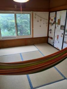 een hangmat in een kamer met 2 ramen bij Tanehachi Farm Guesthouse - Vacation STAY 29709v in Aomori