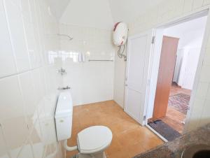 een witte badkamer met een toilet en een wastafel bij Bohemian Hideaway - Vintage Vibe 3BHK Villa in Kodaikānāl