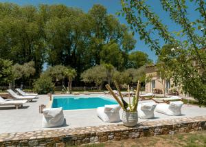 una piscina con tumbonas blancas y una piscina en Natura Bungalows, en Limenas