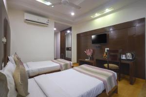 Hotel Haris MG Road Gurugram في جورجاون: غرفه فندقيه سريرين وتلفزيون