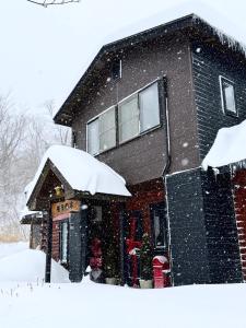 una casa cubierta de nieve delante en Mominoki Lodgeモミの木ロッジ, en Minakami