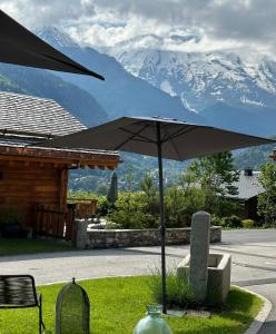 un grand parasol dans l'herbe avec des montagnes en arrière-plan dans l'établissement Hôtel Restaurant La Ferme de Cupelin, à Saint-Gervais-les-Bains