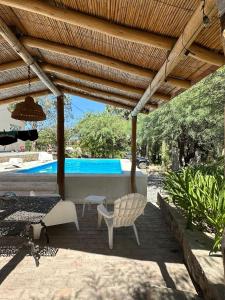 un patio con mesa, sillas y piscina en EL PEDREGAL Casa en Cafayate, en Cafayate