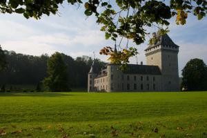 un castillo en un campo de césped con árboles en Chateau Jemeppe, en Marche-en-Famenne