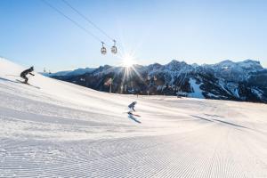 twee personen die skiën op een met sneeuw bedekte piste met een skilift bij Dolomites Smart Holidays in Valdaora