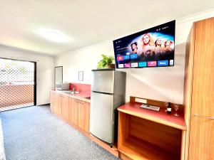 een keuken met een koelkast en een tv aan de muur bij Mackay Resort Motel in Mackay