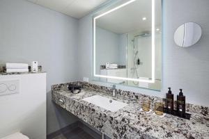 bagno con lavandino e specchio di Dorint Hotel Esplanade Jena a Jena