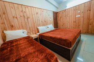 two beds in a room with wooden walls at Vivera Highlands in Kodaikānāl