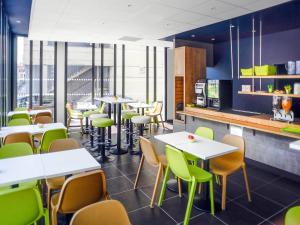 een restaurant met witte tafels en groene stoelen bij ibis budget Gare de Poitiers in Poitiers