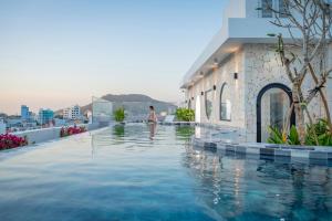 una persona caminando en una piscina al lado de un edificio en V Boutique Hotel - Complimentary refreshments, en Vung Tau