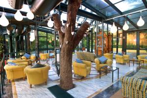 una hall con sedie gialle e un albero al centro di Grand Hotel Bellavista Palace & Golf a Montecatini Terme