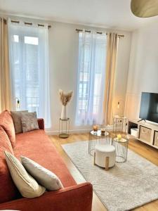 a living room with a couch and a tv at Appartement avec magnifique vue sur la Saône et son balcon in Chalon-sur-Saône