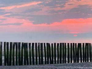 カレーにあるLa Félicita Calais Plageの夕日を望む海岸の木製の柵