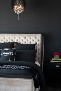 Couture Comfort - Luxe Chanel Themed Apartment في غولد كوست: غرفة نوم بسرير وجدران سوداء وثريا