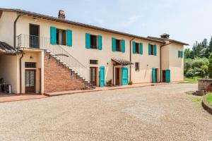 une grande maison avec des volets bleus et une allée. dans l'établissement Podere l'Ulivo, à San Miniato