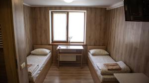 a room with two beds and a desk and a window at Каприз in Kamianets-Podilskyi