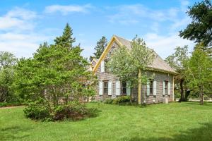 una casa vieja en un césped con árboles en Avonlea Forest Hill Cottages, en New Glasgow