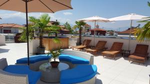 une terrasse avec une piscine, des chaises et un parasol dans l'établissement Harisis Apartments, à Olympiakí Aktí