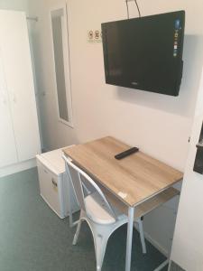 een bureau met een stoel en een televisie aan de muur bij Backpackers Central Hamilton in Hamilton