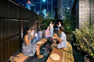 a group of people sitting on a bench in a garden at COGO TENNOJI in Osaka