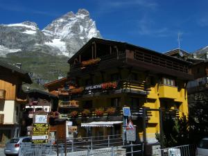 um edifício amarelo em frente a uma montanha em Hotel Meynet em Breuil-Cervinia