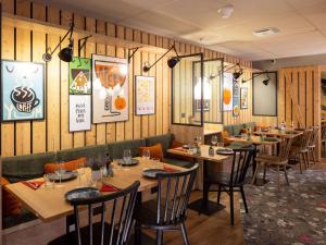 een restaurant met houten wanden en houten tafels en stoelen bij ibis Styles Les Houches Chamonix in Les Houches