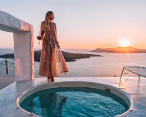 une femme en robe debout à côté d'un bain à remous dans l'établissement Limestone, à Fira