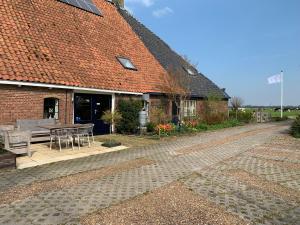 een stenen huis met een patio en een tafel bij Bed and Breakfast de Salix in Hitzum