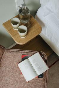 una mesa con dos tazas y un libro al lado de una cama en NINE DOTS Azorean Art Boutique Hotel, en Ponta Delgada