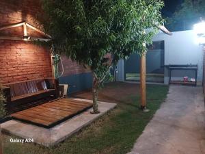 un banco de madera junto a un árbol en un patio en Alojamiento el Ancla, en San Rafael