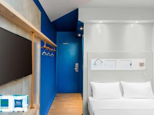 Habitación con cama blanca y pared azul en ibis budget Amiens Centre Gare, en Amiens