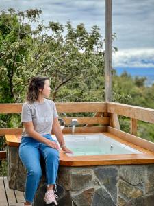 una mujer sentada en un banco junto a un jacuzzi en Cabañas Tungulú, en Puerto Montt