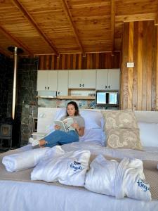 una mujer sentada en una cama leyendo un libro en Cabañas Tungulú, en Puerto Montt