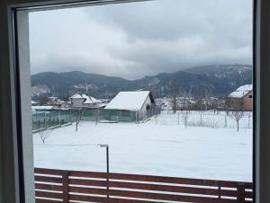 uma vista de um campo coberto de neve a partir de uma janela em Casa Popa em Gura Humorului