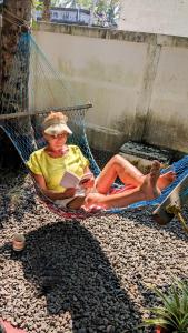 a woman sitting in a hammock reading a book at Dove cottage in Cherai Beach