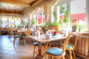 een restaurant met houten tafels, stoelen en ramen bij Hotel am Liepnitzsee in Wandlitz