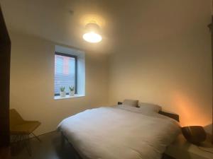 a bedroom with a white bed and a window at Woning Oostende - Oosteroever in Ostend