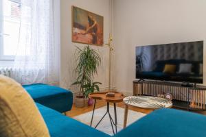 un salon avec un canapé bleu et une télévision dans l'établissement Plumeria - Grand Appartement 75m2 - Au calme - Proche Gare, Nouvelle Ville - Parking Public Gratuit - 2 Chambres - 4 Lits séparés, à Metz