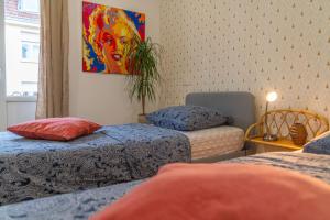 Cette chambre comprend deux lits et un tableau mural. dans l'établissement Plumeria - Grand Appartement 75m2 - Au calme - Proche Gare, Nouvelle Ville - Parking Public Gratuit - 2 Chambres - 4 Lits séparés, à Metz