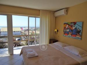 ein Schlafzimmer mit einem großen Bett und einem großen Fenster in der Unterkunft Hotel Aquarella in Punta Del Diablo